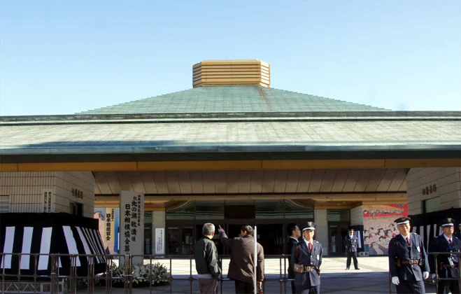 Visitors standing outside the green-roofed Ryogoku Kokugikan