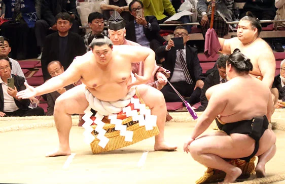 Onosato’s ring-entering ceremony, with an attendant’s fanned topknot visible from behind