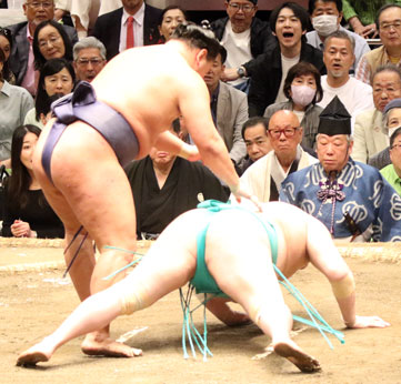 A sumo wrestler throwing his opponent to the clay