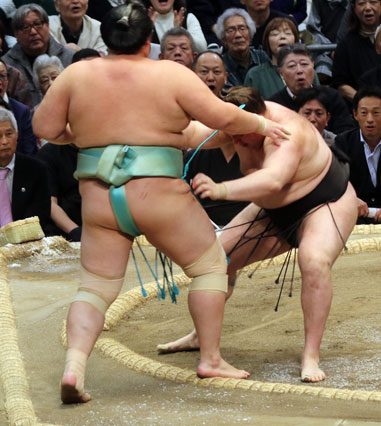 Top-division sumo wrestlers grappling at the center of the ring