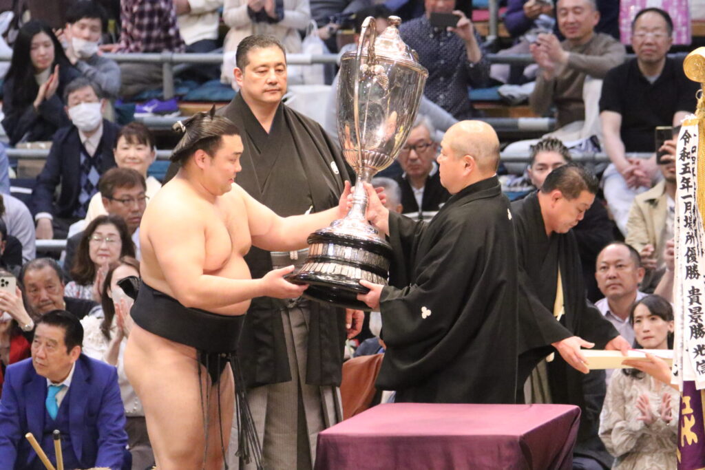 A sumo champion receives the Emperors Cup at the closing ceremony of a grand tournament