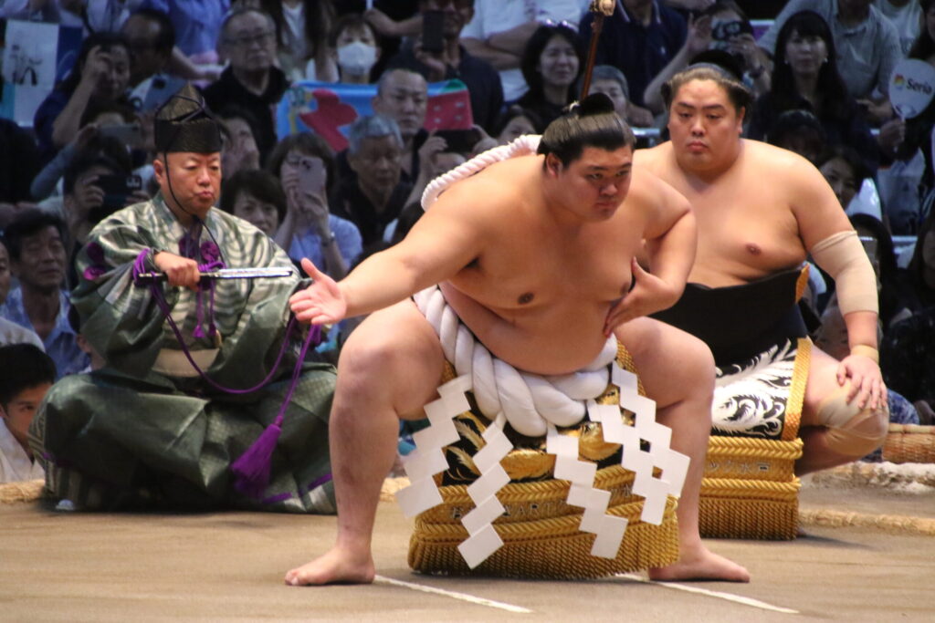 A yokozuna in the white tsuna rope performs the ring-entering ceremony at a grand sumo tournament
