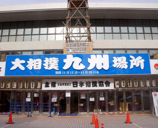 Front entrance of Fukuoka Kokusai Center with the Grand Sumo Kyushu Basho banner and paper lanterns